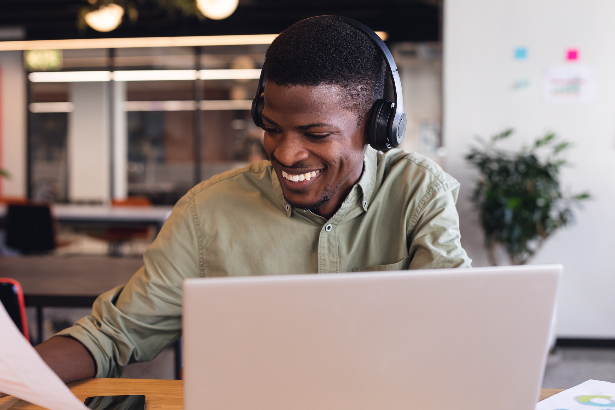 Smiling african american young businessman using laptop in creative office